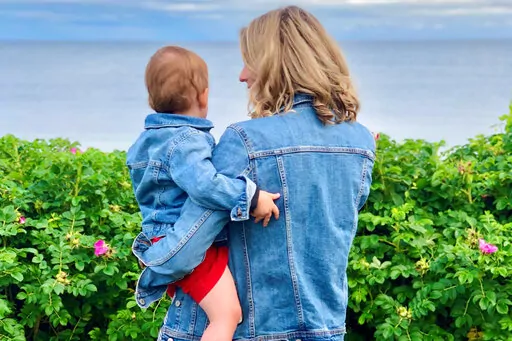 This photo provided by Alex Richer shows his wife, AP writer Alanna Durkin Richer, holding one of their children at Massachusetts' Cape Cod on July 4, 2021. In the aftermath of the May 2022 Uvalde, Texas, school shooting, she writes, "I know rationally that I can’t keep my almost 3-year-old son and his 7-month-old sister in a bubble all their lives. No matter how hard I try, I won't always be able to protect them from harm and pain. But why should I have to fear simply sending them to school?"