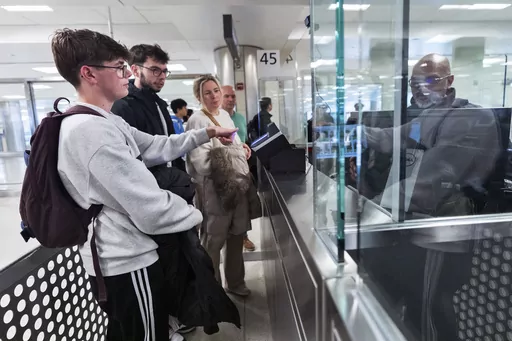 Piet De Staercke, from back right to left, with his wife Jill Bornauw, their eldest son Stan De Staercke, watch their youngest Tuur de Staercke, get screened by a Custom Border Protection officer, right, in the port of entry at Washington Dulles International Airport in Chantilly, Va. Monday, April 1, 2024. The Belgian family of four, used the Mobile Passport Control app, the newest technology in international travel, to ease their way to their port of entry. Within minutes they had bypassed a l