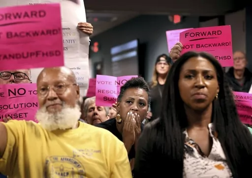 Kimberly Thompson, center, listens as Francis Howell School Board members talk in favor of rescinding all previously passed resolutions, including an anti-racism resolution, during a meeting on Thursday, July 20, 2023 in O'Fallon, Mo. In the national reckoning that followed the police killing of George Floyd three years ago, protesters took to the streets in a St. Louis suburb and urged the mostly-white Francis Howell School District to address racial discrimination. The school board responded w