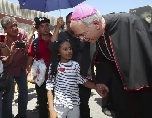 El Paso Catholic Bishop Mark Seitz talks with Celsia Palma, 9, of Honduras, as they walked to the Paso Del Norte International Port of Entry, Thursday, June, 27, 2019, in Juarez, Mexico. (AP Photo/Rudy Gutierrez)