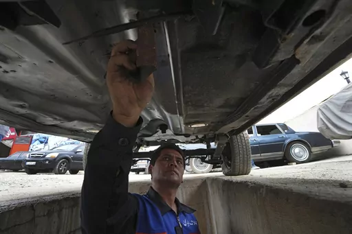 A worker sands an under a restored Cadillac Seville at restorer Khosro Dahaghin's workshop in Roudehen, some 30 miles (45 kilometers) east of downtown Tehran, Iran, Wednesday, June 7, 2023. Dahaghin’s passion for restoring the cars means he carefully examines each frame, component and stitch of the Sevilles in Iran, a challenge that's only grown as parts become scarce, the vehicles get older and as the country faces U.S. sanctions over its nuclear program. (AP Photo/Vahid Salemi)