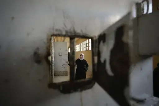 A woman examines the cells at the infamous Saydnaya military prison, just north of Damascus, Syria, on Monday, Dec. 9, 2024. Crowds are gathering to enter the prison, known as the "human slaughterhouse," after thousands of inmates were released following the rebels' overthrow of Bashar al-Assad's regime on Sunday. (AP Photo/Hussein Malla)