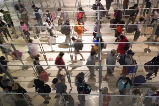 To prevent the spread of COVID-19, plexiglass keeps travelers separated as they make their way through the line to clear security at Love Field in Dallas, Friday, Dec. 31, 2021. (AP Photo/LM Otero)