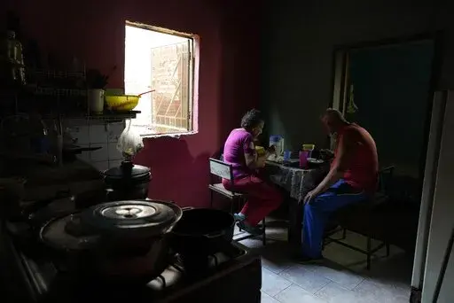 Elderly married couple Maybel Sequera and Juan Gonzalez eat lunch at home in the low-income neighborhood of La Vega in Caracas, Venezuela, Thursday, April 7, 2022. Their lunch was a gift from a nonprofit organization, as the seamstress and retired driver cannot afford to feed themselves on their monthly pensions and have to rely on donations for food, medicines and clothing. (AP Photo/Ariana Cubillos)