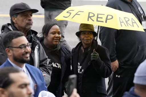Pia Harris, with the San Francisco Housing Development Corporation, second from left, and her mother, Adrian Williams, listen to speakers at a reparations rally outside of City Hall in San Francisco, Tuesday, March 14, 2023. Harris hopes for reparations in her lifetime. But the nonprofit program director is not confident that California lawmakers will turn the recommendations of a first-in-the-nation task force into concrete legislation, given the pushback from opponents who say slavery was a th