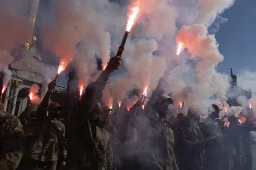 Soldiers of Ukraine's Azov battalion light flares at a rally demanding to free Ukrainian prisoners of war who are held in captivity in Russia at Independence Square in Kyiv, Ukraine, Sunday, July 28, 2024. Several thousand people and soldiers gathered to commemorate the second anniversary of a Russia-orchestrated explosion that killed more than 50 Ukrainian prisoners of war in the Russian-held Olenivka prison barracks. (AP Photo/Efrem Lukatsky)