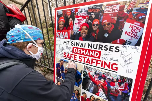 Zach Clapp, a nurse in the Pediatric Cardiac ICU at Mount Sinai Hospital signs a board demanding safe staffing during a rally by NYSNA nurses from NY Presbyterian and Mount Sinai, Tuesday, March 16, 2021, in New York. Negotiations to keep 10,000 New York City nurses from walking off the job headed Friday, Jna. 6, 2023, into a final weekend as some major hospitals braced for a potential strike by sending ambulances elsewhere and transferring such patients as vulnerable newborns. (AP Photo/Mary Al