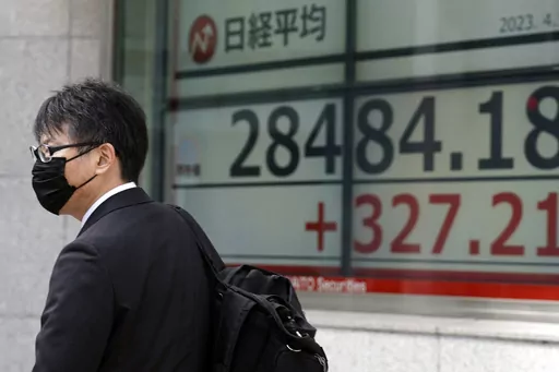 A person walks past in front of an electronic stock board showing Japan's Nikkei 225 index at a securities firm Friday, April 14, 2023, in Tokyo. Asian stock markets followed Wall Street higher on Friday after U.S. inflation eased in March and China reported unexpectedly strong exports. (AP Photo/Eugene Hoshiko)