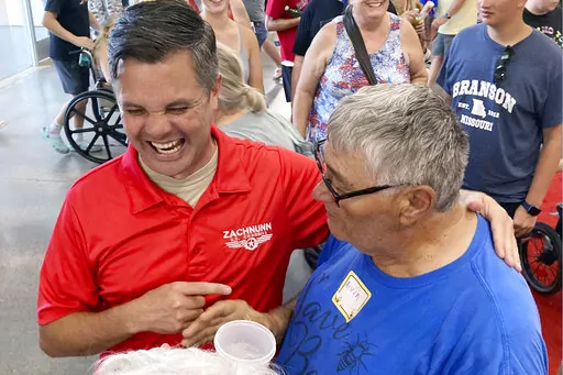 Iowa Republican candidate for Congress Zach Nunn, left, laughs while talking with Arvin Foell of Kelley, Iowa, during an appearance at the Iowa State Fair, in Des Moines, Iowa, August 12, 2022. Nunn is among more than a dozen strict abortion opponents running in competitive House, Senate and governor races working to soften his profile in light of increased enthusiasm among Democratic voters since the June U.S. Supreme Court decision reversing a federal right to abortion. (AP Photo/Thomas Beaumo