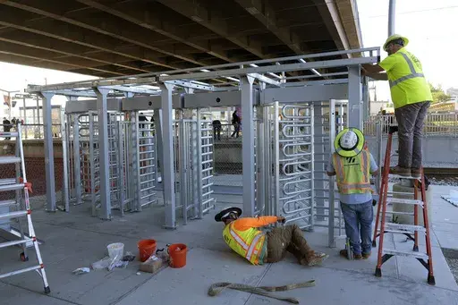Workers install a metal gate that will prevent customers from entering a MetroLink platform without a valid fare card in an effort to increase security Wednesday, Oct. 9, 2024, in St. Louis. (AP Photo/Jeff Roberson)