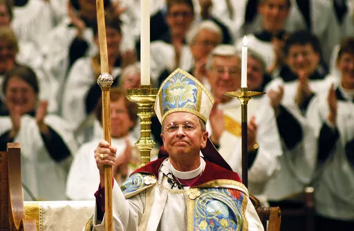 FILE - Gene Robinson is applauded after his investiture as the Episcopal Church's bishop of New Hampshire at St. Paul's Church in Concord, N.H., on Sunday, March 7, 2004. In 2008, when Robinson was excluded from a global Anglican gathering because of his sexuality, Desmond Tutu, who died Sunday, Dec. 26, 2021, came to his defense. (AP Photo/Lee Marriner, File)