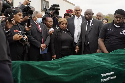 Civil rights attorney Ben Crump, center right, Bettersten Wade, center, mother of Dexter Wade, a 37-year-old man who died after being hit by a Jackson, Miss., police SUV driven by an off-duty officer, watches her son's body transferred to a mortuary transport after being exhumed from a pauper's cemetery near the Hinds County Penal Farm in Raymond, Monday, Nov. 13, 2023. After men in near Mississippi's capital were buried in a pauper’s cemetery without their relatives’ knowledge, the U.S. Jus
