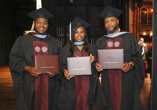 In this photo provided by Mississippi State University - Meridian Office of Public Affairs, Ja'Coby Cole, left, his sister Iesha Gully and their father Commondre Cole, right, show their diploma covers, on Thursday, May 12, 2022, during the school's commencement at the MSU Riley Center in Meridian, Miss. Each of the three earned a master's degree in education. (Lisa Sollie/Mississippi State University - Meridian via AP)