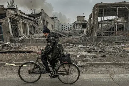 A man rides on a bike in front of the mail office which was destroyed by a Russian airstrike in Kurakhove, Donetsk region, Ukraine, on Nov. 7, 2024. (AP Photo/Anton Shtuka)