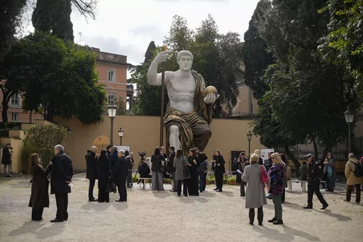 Visitors admire a massive, 13-meter (yard) replica of the statue Roman Emperor Constantine commissioned for himself after 312 AD that was built using 3D technology from scans of the nine giant original marble body parts that remain, as it was unveiled in Rome, Tuesday, Feb. 6, 2024. The imposing figure of a seated emperor, draped in a gilded tunic and holding a scepter and orb, gazing out over his Rome, is located in a side garden of the Capitoline Museums, just around the corner from the courty