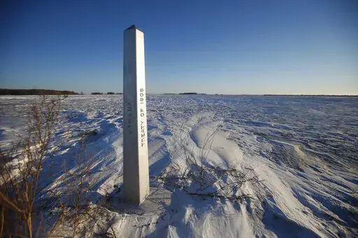 A border marker, between the United States and Canada is shown just outside of Emerson, Manitoba, on Thursday, Jan. 20, 2022.  A Florida man was charged Thursday with human smuggling after the bodies of four people, including a baby and a teen, were found in Canada near the U.S. border, in what authorities believe was a failed crossing attempt during a freezing blizzard. The bodies were found Wednesday in the province of Manitoba just meters (yards) from the U.S. border near the community of Eme