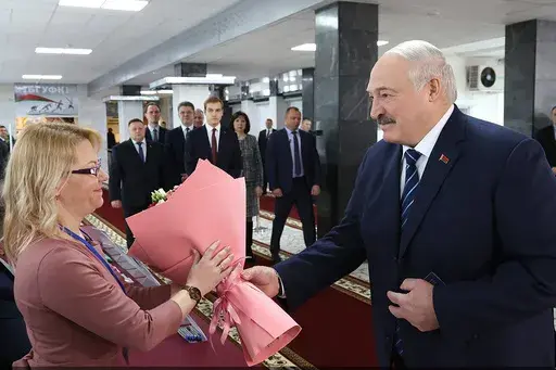 In this photo provided by the Belarusian Presidential Press Service, Belarus President Alexander Lukashenko, right, presents flowers to an election commission official ahead of voting at a polling station, in Minsk, Belarus, Sunday, Feb. 25, 2024. Lukashenko was believed a few years ago to be considering whether to lead the new body after stepping down, but his calculus has apparently changed, and he announced on Sunday that he will run in next year's presidential election. (Belarusian President