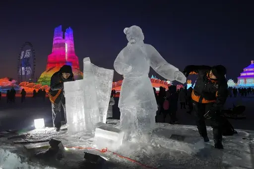 Artists work on a ice sculptures as visitors tour the illuminated ice structures at the Harbin Ice and Snow World in Harbin, China's Heilongjiang province on Sunday, Jan. 5, 2025. (AP Photo/Andy Wong)