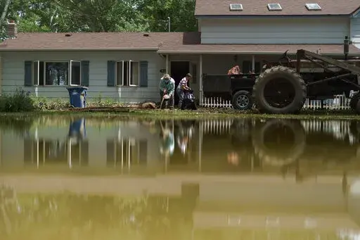 Aileen Rogers, right, and Melody Murter help clean out a friend's house badly damaged by the severe flooding in Fromberg, Mont., Friday, June 17, 2022. (AP Photo/David Goldman)