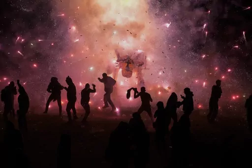 People dance and dodge a giant paper-mache bull stuffed with fireworks as roman candles and bottle rockets shower them with sparks, during the annual festival honoring Saint John of God, in Tultepec, Mexico, Friday, March 8, 2024. The celebration, now its 35th year, pays homage to the patron saint of the poor and sick, St. John of God, who the fireworks' producers view as a protective figure. (AP Photo/Marco Ugarte)