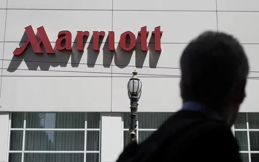 A person walks past the San Francisco Marriott Union Square hotel on July 11, 2019, in San Francisco. Multinational companies including Amazon, Marriott and Hilton pledged Monday June 19, 2023 to hire more than 13,000 refugees, including Ukrainian women who have fled the war with Russia, over the next three years in Europe. (AP Photo/Jeff Chiu, File)