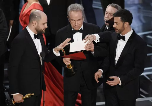 "La La Land" producer Jordan Horowitz, left, presenter Warren Beatty, center, and host Jimmy Kimmel right, look at an envelope announcing "Moonlight" as best picture at the Oscars on Sunday, Feb. 26, 2017, in Los Angeles. It was originally announced mistakenly that "La La Land" was the winner. (Photo by Chris Pizzello/Invision/AP, File)
