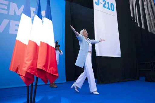 FILE- Marine Le Pen walks on stage, at a National Rally event in Frejus, Sunday, Sept. 12, 2021. French nationalist Marine Le Pen has softened her rhetoric and her image as she tries to unseat centrist President Emmanuel Macron in the upcoming election, taking place in two rounds on April 10 and 24. She is honing in on the pocketbook issues that voters care about most. But the woman who has been known for her fierce anti-immigration stance is also facing a challenge from TV pundit Eric Zemmour, 