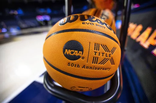 FILE- A basketball with an NCAA logo and a Title IX inscription rests on a rack before a First Four game between Illinois and Mississippi State at the NCAA women's college basketball tournament Wednesday, March 15, 2023, in South Bend, Ind. The NCAA, the organization that governs college athletics, was once at the forefront of hot-button issues such as the Confederate flag and transgender rights. But that stance evolved quickly as one Republican-controlled state after another rushed to pass laws