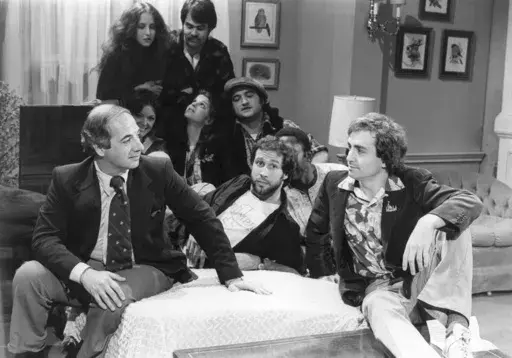 White House Press Secretary Ron Nessen, left, appears on the "Saturday Night Live" set with producer Lorne Michaels, right, and cast members Chevy Chase, foreground center, Laraine Newman, background left, Dan Aykroyd, background right, Jane Curtain, second row from left, Gilda Radner, John Belushi and Garret Morris, partially obscured, on April 17, 1976, in New York. (AP Photo)