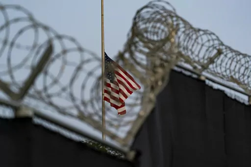 In this photo reviewed by U.S. military officials, a flag flies at half-staff in honor of the U.S. service members and other victims killed in the terrorist attack in Kabul, Afghanistan, as seen from Camp Justice in Guantanamo Bay Naval Base, Cuba, Aug. 29, 2021. The first U.N. independent investigator to visit the U.S. detention center at Guantanamo Bay said Monday, June 26, 2023, that the 30 men held there are subject “to ongoing cruel, inhuman and degrading treatment under international law