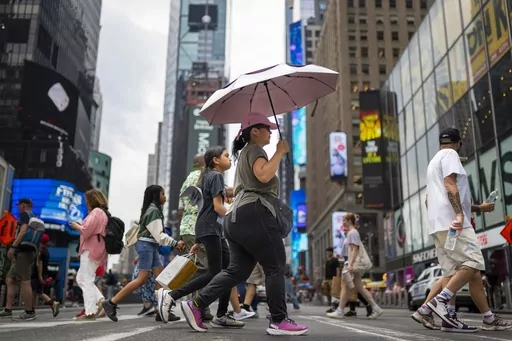 A pedestrian uses an umbrella to shield against the sun while passing through Times Square as temperatures rise, July 27, 2023, in New York. At about summer's halfway point, the record-breaking heat and weather extremes are both unprecedented and unsurprising, hellish yet boring in some ways, scientists say. (AP Photo/John Minchillo, File)