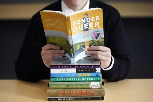 Amanda Darrow, director of youth, family and education programs at the Utah Pride Center, poses with books that have been the subject of complaints from parents on Dec. 16, 2021, in Salt Lake City. With legislators in Florida barring even the mention of being gay in classrooms and similar restrictions being considered in other states, books with LGBTQ+ themes remain the most likely targets of bans or attempted bans at public schools and libraries around the country, according to a new report Mon