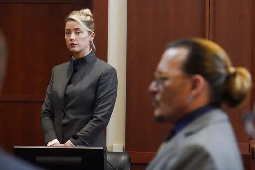 Actors Amber Heard and Johnny Depp watch as the jury leaves the courtroom for a lunch break at the Fairfax County Circuit Courthouse in Fairfax, Va., Monday, May 16, 2022. A new court filing on Friday, July 8, 2022, from Heard's legal team, alleges one of the jurors in the defamation case filed against her by her ex-husband Depp served improperly. (AP Photo/Steve Helber, Pool, File)