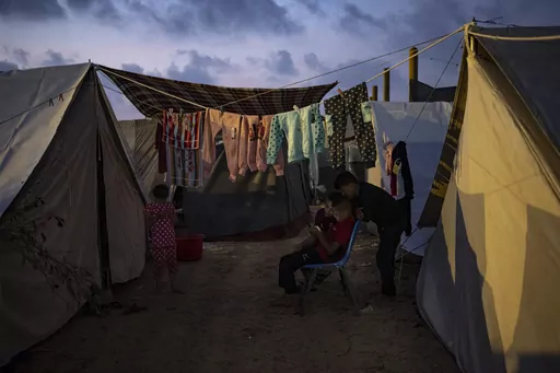 Palestinian kids, who were displaced by the Israeli bombardment of the Gaza Strip, watch a phone in a UNDP-provided tent camp in Khan Younis, Gaza Strip, Wednesday, Nov. 1, 2023. While journalists' access to the war in Gaza is limited, a flood of video from all sorts of sources documents what is — and isn't — going on. (AP Photo/Fatima Shbair, File)