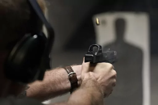 A man fires his pistol at an indoor shooting range during a qualification course to renew his Carry Concealed handgun permit at the Placer Sporting Club, July 1, 2022, in Roseville, Calif. A federal judge on Wednesday, Dec. 20, 2023, temporarily blocked a California law that would have banned carrying firearms in most public places, ruling that it violates the Second Amendment of the U.S. Constitution and deprives people of their ability to defend themselves and their loved ones. (AP Photo/Rich 