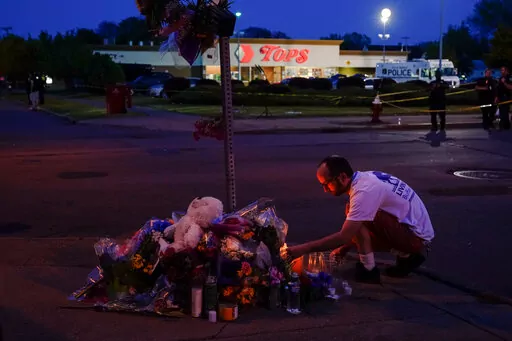 A person pays his respects outside the scene of a shooting at a supermarket, in Buffalo, N.Y., Sunday, May 15, 2022. (AP Photo/Matt Rourke)