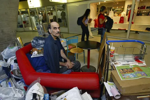 Merhan Karimi Nasseri sits among his belongings at Terminal 1 of Roissy Charles De Gaulle Airport, north of Paris on Aug. 11, 2004 . An Iranian man who lived for 18 years in Paris' Charles de Gaulle Airport and inspired the Steven Spielberg film "The Terminal" died Saturday, Nov. 12, 2022 in the airport, officials said. Merhan Karimi Nasseri died after a heart attack in the airport's terminal 2F around midday, according an official with the Paris airport authority. Police and then a medical team