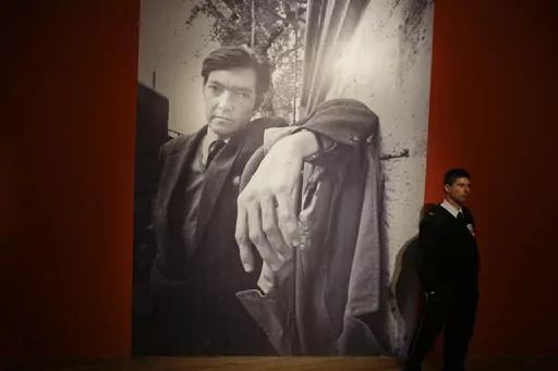 A security guard stands near a large photo of late writer Julio Cortazar at an exhibit marking the 100-year anniversary of his birth at the National Museum of Fine Arts in Buenos Aires, Argentina, Aug. 26, 2014. A bundle of 60-year-old pages of Cortazar´s writings was sold at auction on Thursday, October 12, 2023, by the Zorrilla de Montevideo auction house. (AP Photo/Victor R. Caivano, File)