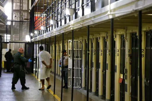 In this Aug. 16, 2016, file photo a condemned inmate is led out of his east block cell on death row at San Quentin State Prison, in San Quentin, Calif. California Gov. Gavin Newsom is moving to dismantle the nation's largest death row by moving all condemned inmates to other prisons with in two years. The goal is to turn the section of San Quentin State Prison into "a positive, healing environment." (AP Photo/Eric Risberg, File)