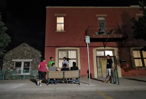 Migrant parents socialize outside the Annunciation House, June 26, 2018, in El Paso, Texas. A Texas judge ruled against the state attorney general on Tuesday, July 2, 2024, in his effort to shut down a migrant shelter in El Paso that he claimed encourages illegal migration. (AP Photo/Matt York, File)
