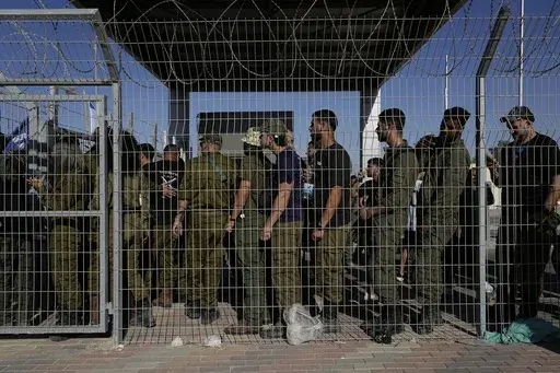 Israeli soldiers gather at the gate to the Sde Teiman military base, as people protest in support of soldiers being questioned for detainee abuse, July 29, 2024. (AP Photo/Tsafrir Abayov, File)