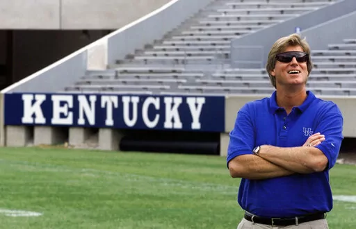 Kentucky coach Hal Mumme smiles as he waits for a photo shoot during the team's media day on Aug. 12, 1999, at Commonwealth Stadium in Lexington, Ky. Of the top 25 most-prolific passing seasons in major college football history by yards per game, 12 have direct connections to Mumme and Mike Leach — from Kentucky to Houston to Texas Tech to New Mexico State to Washington State. (AP Photo/Ed Reinke, File)