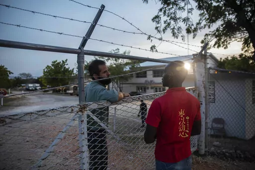 A manager at the Christian Aid Ministries headquarters, left, speaks with a worker at the door of the center in Titanyen, north of Port-au-Prince, Haiti, Sunday, Nov. 21, 2021. A year after 17 North American missionaries were kidnapped in Haiti, beginning a two-month ordeal before they ultimately went free, Christian Aid Ministries, the agency that sent them hasn't made a permanent return, and several other international groups have also scaled back their work there. (AP Photo/Odelyn Joseph)