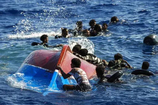 Migrants swim next to their overturned wooden boat during a rescue operation by Spanish NGO Open Arms at south of the Italian Lampedusa island at the Mediterranean sea, Aug. 11, 2022. The back-to-back shipwrecks of migrant boats off Greece that left at least 22 people dead this week has once again put the spotlight on the dangers of the Mediterranean migration route to Europe. (AP Photo/Francisco Seco, file)
