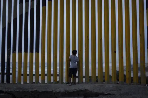 A boy looks through a border wall separating Mexico from the United States, Nov. 26, 2024, in Tijuana, Mexico. (AP Photo/Gregory Bull, File)