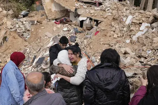Displaced residents hug as they stand in front of the rubble of their destroyed house in Baalbek, eastern Lebanon, Thursday, Nov. 28, 2024. (AP Photo/Hassan Ammar)
