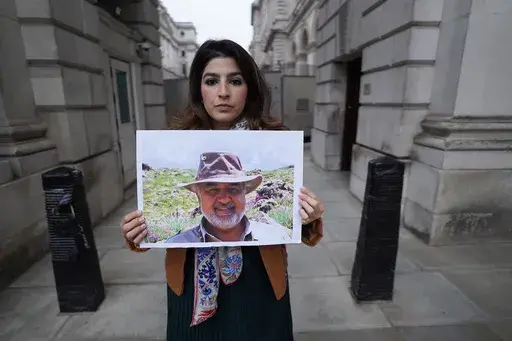Roxanne Tahbaz holds a picture of her father Morad Tahbaz who is jailed in Iran, during a protest outside the Foreign, Commonwealth and Development Office in London, April 13, 2022. Iran has transferred five Iranian-Americans from prison, identifying three of the prisoners as Siamak Namazi, Emad Shargi, and Morad Tahbaz, to house arrest. The move comes after Tehran has spent months suggesting a prisoner swap with Washington. (Stefan Rousseau/PA via AP, File)