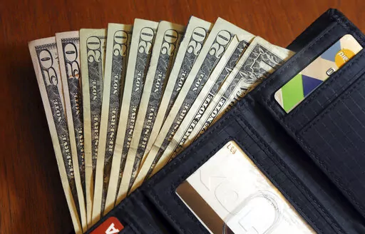 In this June 15, 2018, file photo, cash is fanned out from a wallet in North Andover, Mass. Following a family budget is challenging, especially when unexpected costs pop up, including those related to the high prices at the grocery store and rising interest rates. Financial experts say you can overcome those obstacles by creating a flexible approach to managing your money. Start by tracking your spending, leaving room for some unplanned expenses and cutting back where you can, especially on foo