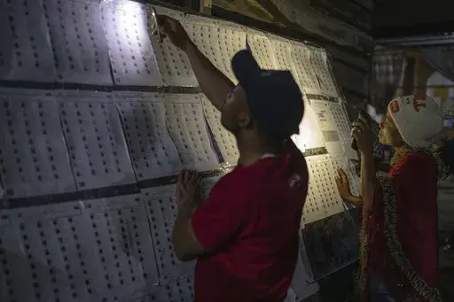 Voters look for their names outside a polling station in Goma, eastern Democratic Republic of the Congo, Wednesday, Dec. 20, 2023. Congo headed to the polls Wednesday to vote for president as authorities scrambled to finalise preparations in an election facing steep logistical and security challenges. (AP Photo/Moses Sawasawa)
