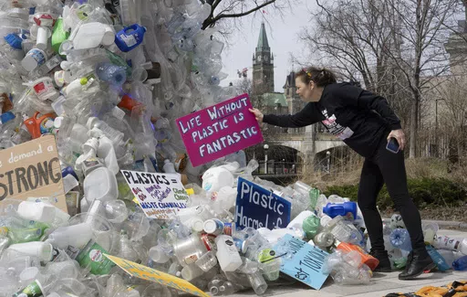Activist Dianne Peterson places a sign on an art installation outside a United Nations conference on plastics, April 23, 2024, in Ottawa, Ontario. (Adrian Wyld/The Canadian Press via AP. File)